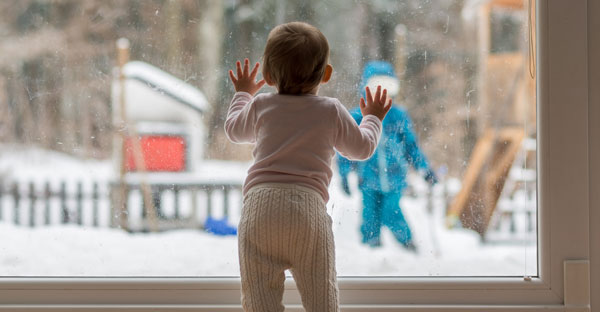 Una niña observa una escena invernal por la ventana